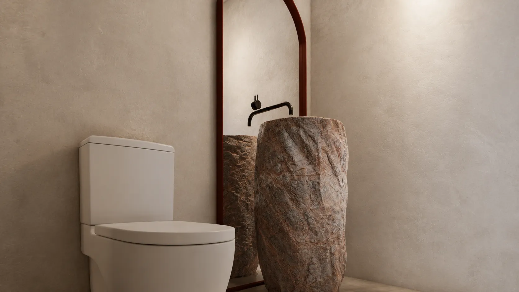 Baño del estudio con lavabo monolítico de piedra y espejo de arco enmarcado en granate.